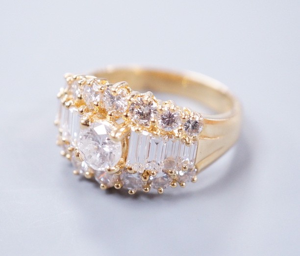 A modern 18ct gold and graduated round and baguette cut diamond set three row cluster ring, size M, gross weight 7.4 grams